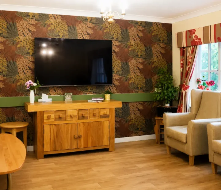 Welcoming communal lounge at Ladymead nursing and residential care home in Swindon, with comfortable seating and a large TV.