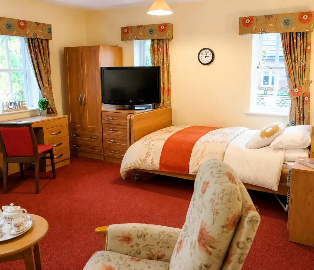 Spacious bedroom at Ladymead nursing and residential care home in Swindon, with comfortable furnishings and seating.