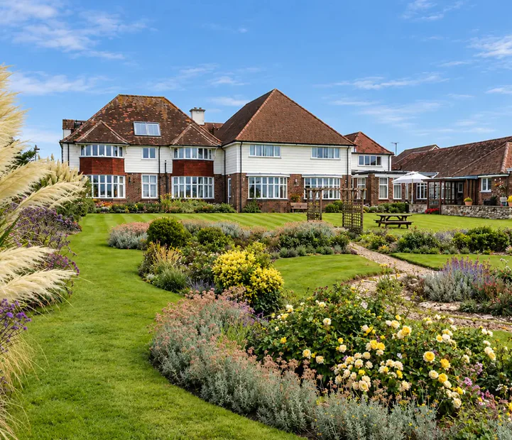Rear exterior of Tenchley Manor residential and nursing care home in Chichester, surrounded by landscaped gardens.