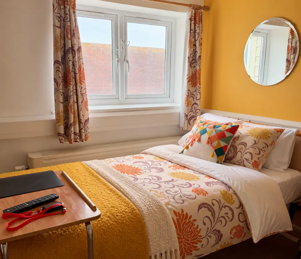 Comfortable furnished bedroom with floral bedding at Tenchley Manor care home in Chichester.