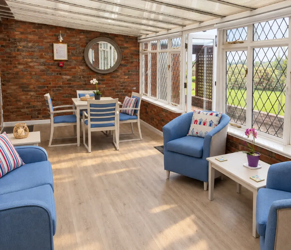 Bright conservatory at Tenchley Manor care home in Chichester, with comfortable seating and garden views.