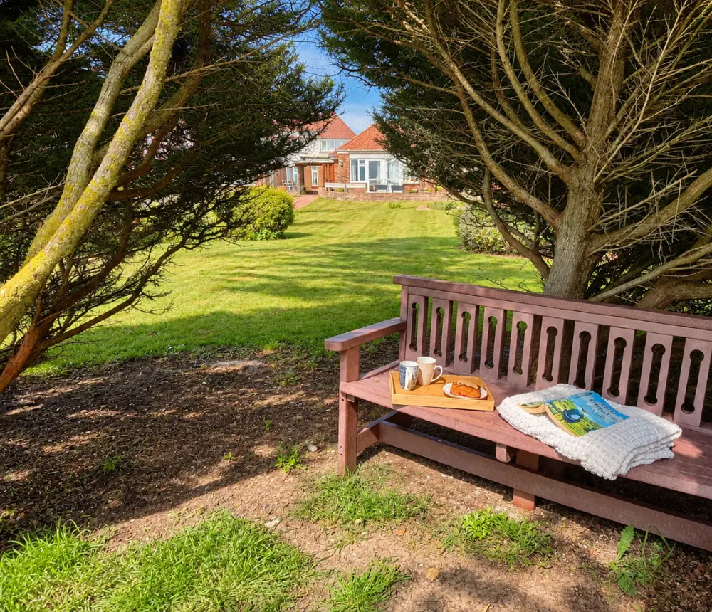 Wooden garden bench in a peaceful shaded area at Tenchley Manor care home in Chichester.