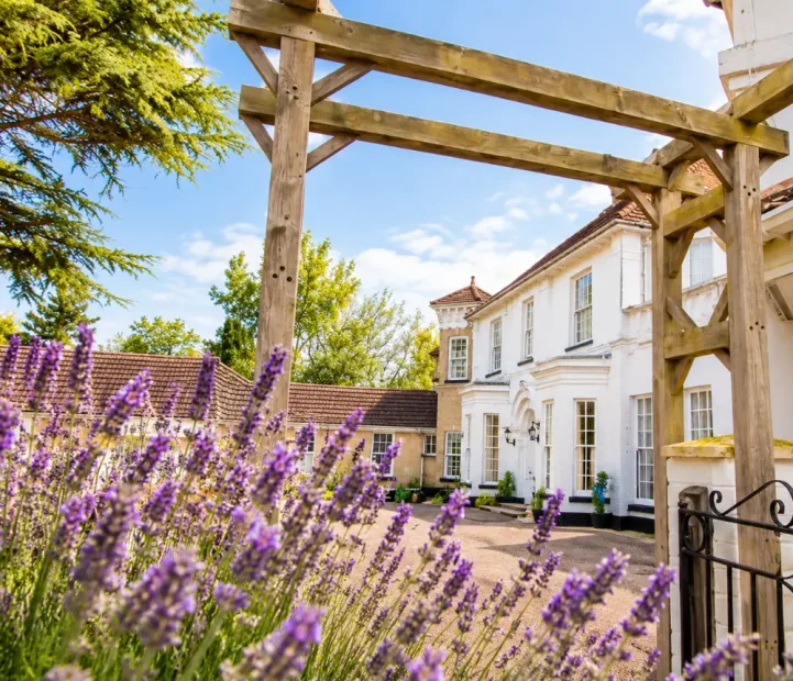 White House care home in Beccles viewed through a wooden pergola and flowering lavender.