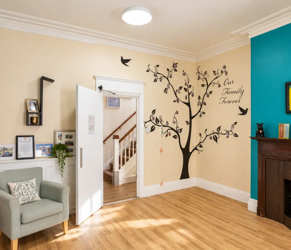 Communal lounge with family tree wall display at The White House care home in Beccles.