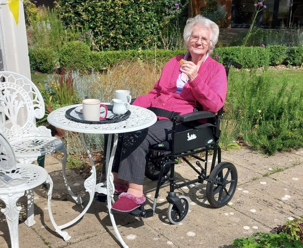 Joan, 93-year-old resident of Maynell House care home, sitting outside and enjoying the gardens on a sunny day.