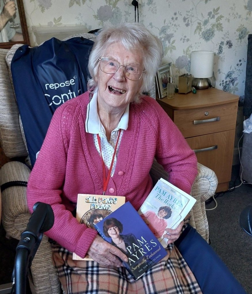 Joan, 93-year-old resident of Maynell House care home, proudly holding her collection of Pam Ayres books.