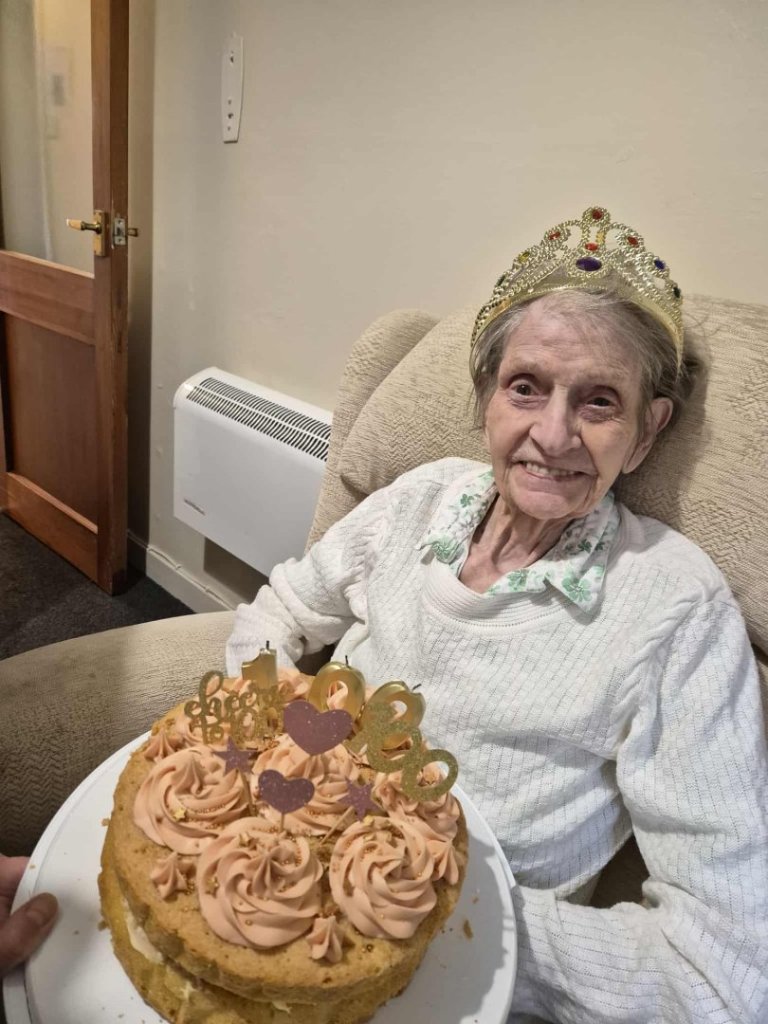Joan Bedford, one of four centenarians at North Walsham care home, holding her 100th birthday card from His Majesty The King