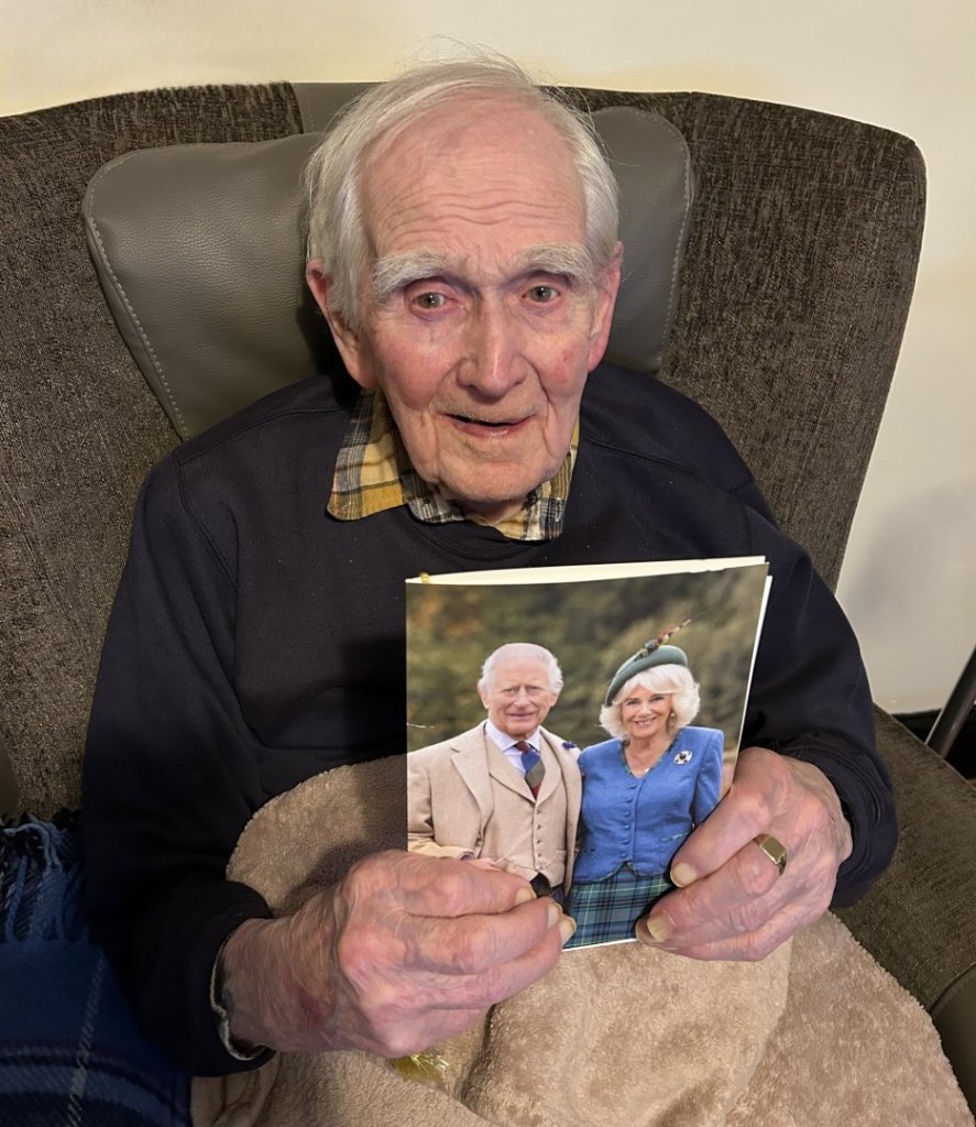 Noel Buck, a centenarian at North Walsham care home, holding his 100th birthday card from His Majesty The King