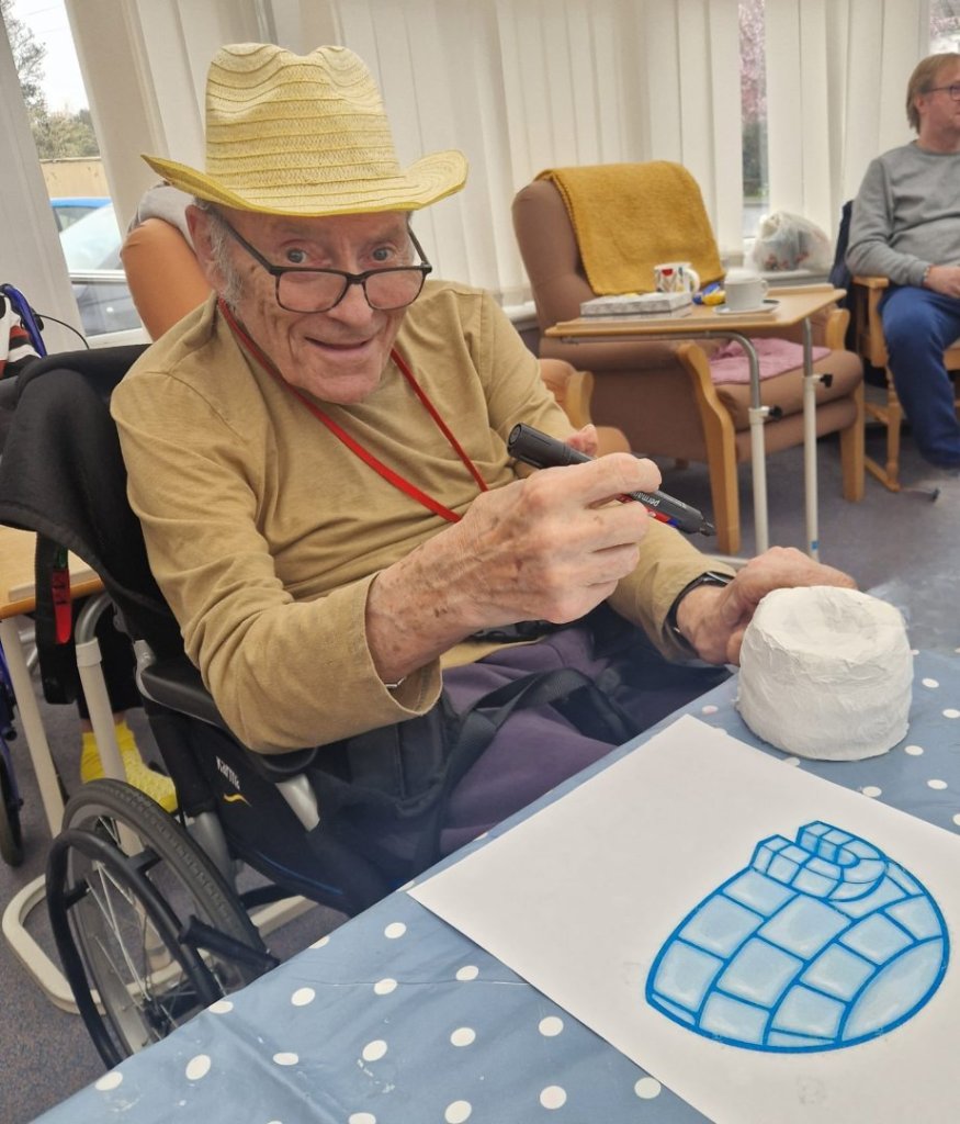 Residents smiling and holding paper plate polar bear crafts during International Polar Bear Day at Bedhampton Court.