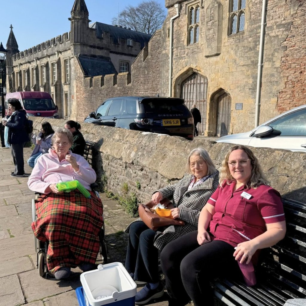 Residents from The Malthouse enjoying the grounds outside Wells Cathedral on a day trip