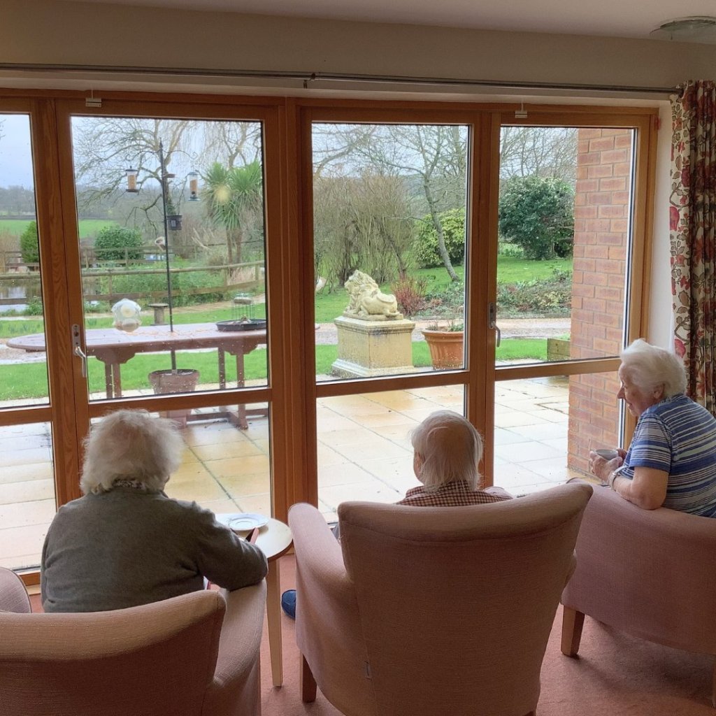 Resident looking out at the gardens from a window at The Old Vicarage care home.