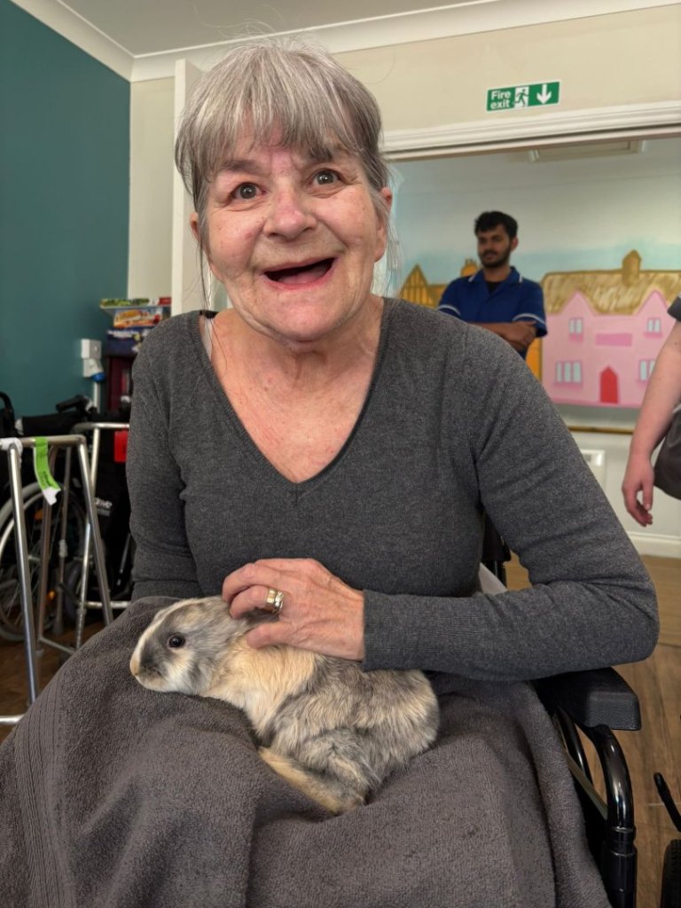 Resident holding rabbit during care home animal visit at Barking Hall Nursing Home