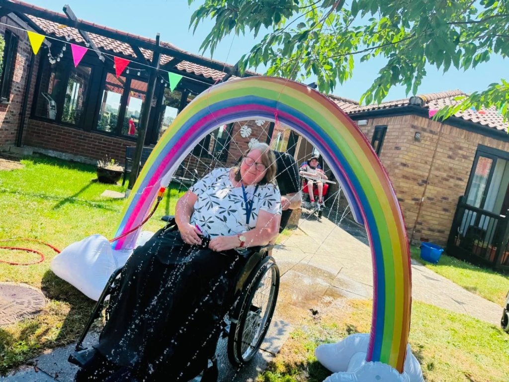 Rainbow sprinkler arch set up in the Meadow House garden for a wheelchair wash activity