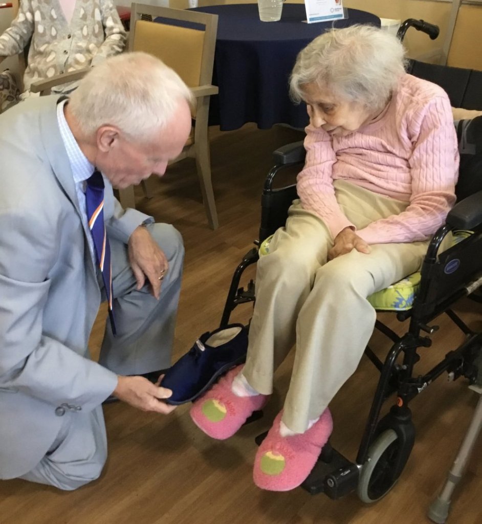 Michael Hatch trying a fluffy slipper on a resident during Avon Lodge's Disney day